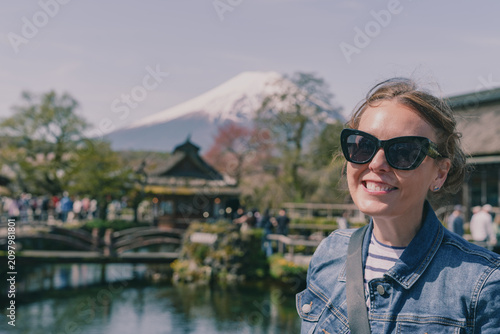 Woman wearing sunglasses poses with at Oshino Hakkai traditional thatched roof village near Mt Fuji, Japan