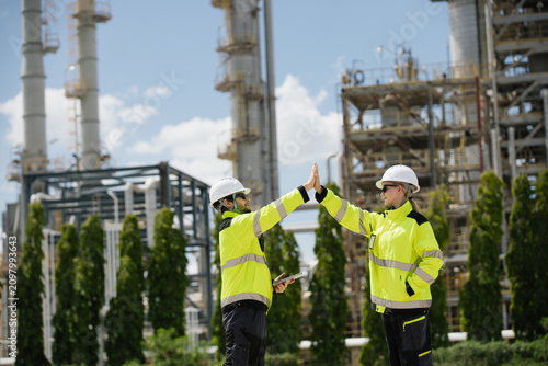 Team of engineers sharing a joyful moment with a high five in front of a contemporary industrial construction site