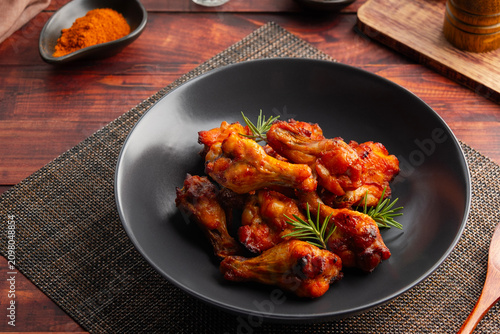 Spicy marinated chicken drumettes wing in black plate.