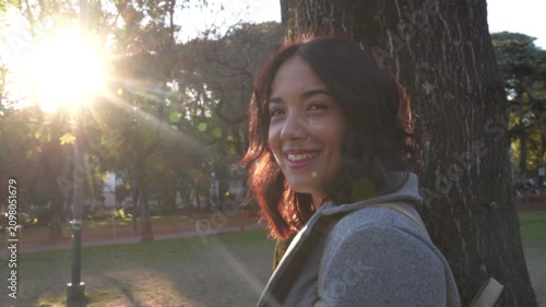 Beautiful hispanic woman smiling at camera in park at sunset