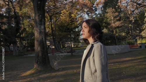 Young businesswoman walking alone in the park at sunset
