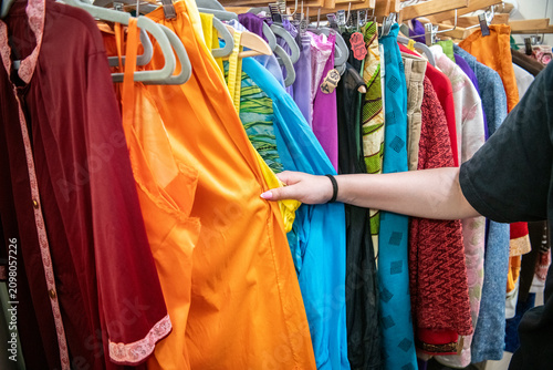 Quadro su tela Hand selecting colorful clothing in a thrift shop or resale boutique