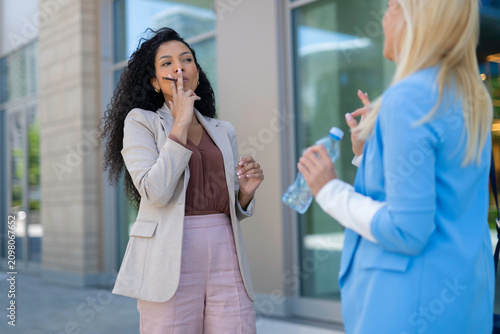Businesswomen talking during a break enjoying vape in city