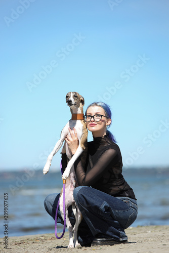 young woman with blue hair holding whippet dog outdoors