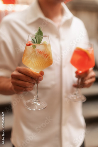 Man Holding Two Colorful Cocktails at Event
Elegant Summer Cocktails Served by Bartender
Refreshing Orange and Red Drinks in Wine Glasses