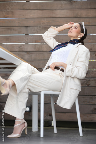 Young businesswoman in beige suit with navy scarf smiling confidently