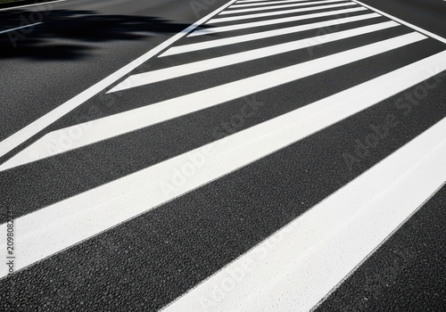 Thick white stripes painted on a dark asphalt road create a bold pattern for safety in a quiet urban setting during the bright daylight, connection, texture, outdoors