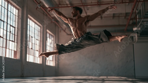 Dancer Leaps in Mid-Air in a Spacious Industrial Dance Studio During a Contemporary Performance Capturing Movement and Energy