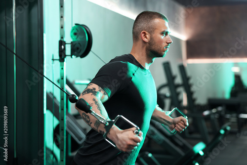 Fotografie Strong man training on cable crossover machine in gym