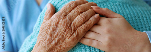  emotional close-up shot of a young nurse's hand and elderly woman's hand 