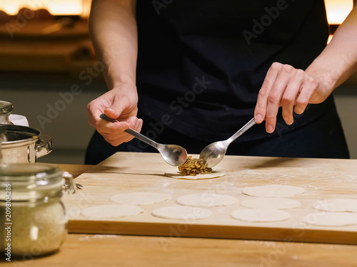 Photos Hands filling dumplings with mushroom stuffing on wooden board, homemade cooking