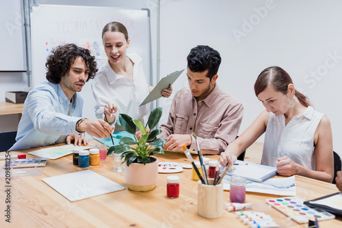 Diverse group of young people in painting class together in a bright studio classroom. Multicultural group of adults men and women engaged in a creative art project