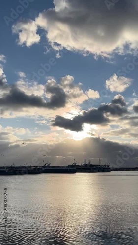 Sun hiding behind the clouds. The view to the port with ships far moored to the port in Istanbul