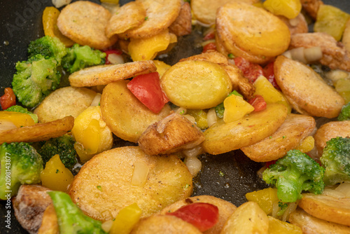 Canvastavla Cooking sliced potatoes with colorful vegetables in a pan at a kitchen during mi