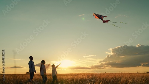 Fotografía Happy family with child playing with kite in meadow