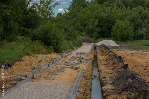 Obraz na płótnie crushed stone, sand and curbstone next to a ditch with water