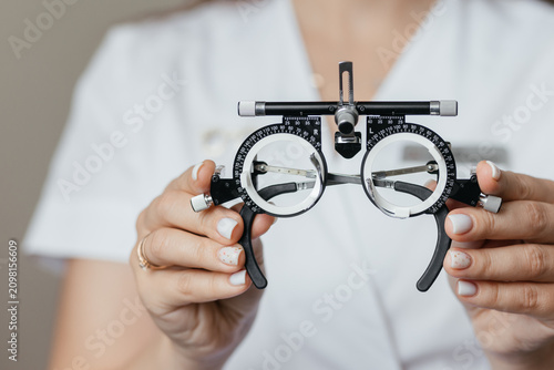 Schilderij op canvas Close-up of ophthalmologist holding trial frame for visual acuity testing in an eye care clinic