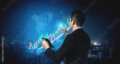 Bild auf Leinwand A business professional stands in a cityscape at night, analyzing digital financial data with a tablet