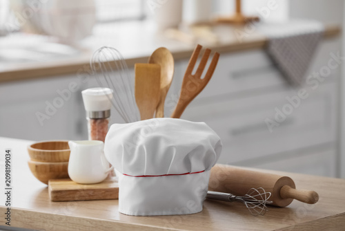 Chefs hat and utensils on w...
