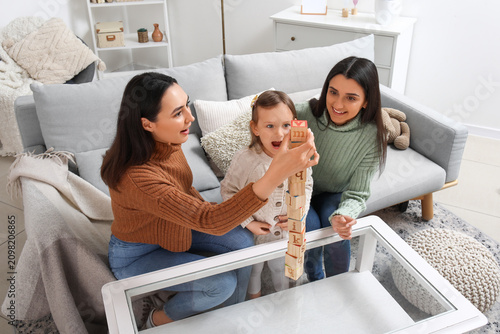 Young lesbian couple and adopted little girl playing with cubes at home