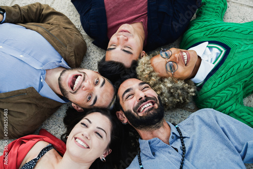 Obraz na płótnie Young diverse people having fun together outdoor lying in circle - Focus on righ