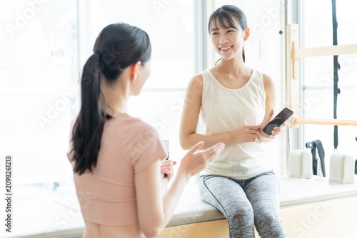 ピラティススタジオでスマートフォンを見せる女性