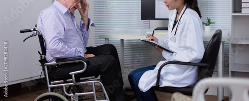 Фотография Senior man in wheelchair feeling unwell and distressed, consulting with a female
