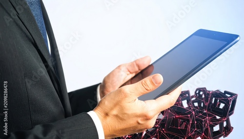 Professional businessman holds a digital tablet interacting with a futuristic 3D rendered network of glowing red cubes symbolizing data and blockchain technology.
