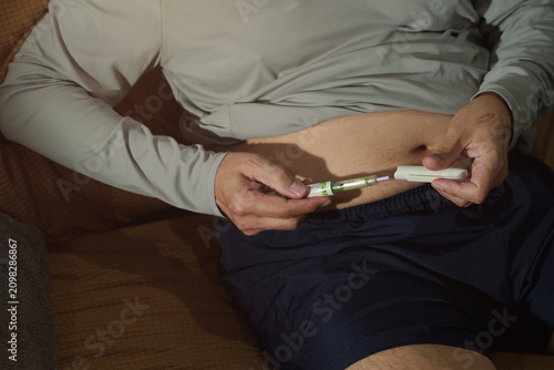 Foto An elderly man is injecting himself with a drug into his abdomen.