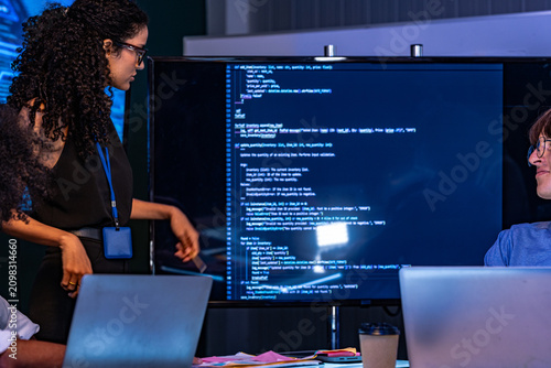 Fotografia Candid moment as a curly-haired developer and a bespectacled coder talk over the