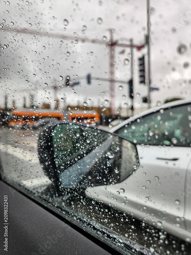 A moody urban commute on a rainy day, viewed from inside a vehicle through a water-spotted window