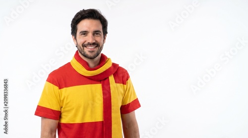 Smiling man wearing a red and yellow fan outfit, isolated on a white background. Perfect for sports supporter concepts.