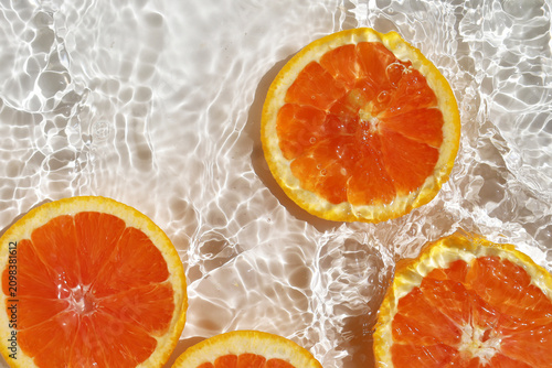 фотографія Juicy Cara Cara orange slices floating in clear, rippling water.
