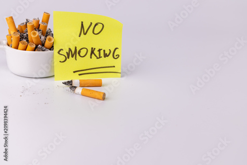 Cuadro en lienzo White ceramic ashtray full of filthy cigarette butts next to a bright yellow sti
