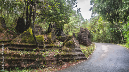 Foto Red-brown boulders with bizarre shapes and undulating slopes with geological layers are on the side of the road