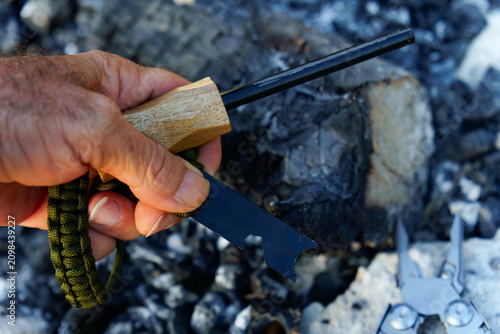 Εκτύπωση καμβά Hand holding a ferrocerium rod and striker, ready to ignite a fire over embers f
