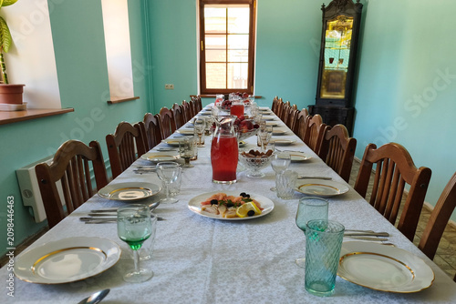 A long table with tablecloths and cutlery is set for meals.