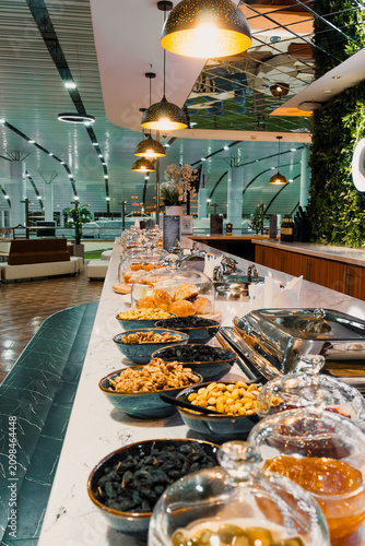 Assorted snacks on serving counter inside airport business lounge, including nuts, olives and fresh pastries in premium waiting area