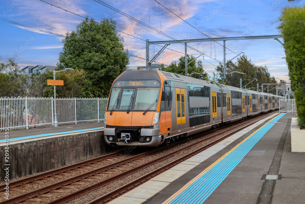 Fototapeta premium Passenger Train going through Lewisham Train Station at Sunset a suburban Sydney train Station in Sydney NSW Australia