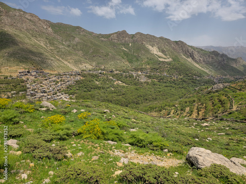 Yellow wildflowers and rocky greenery cover a hillside overlooking a mountain village nestled in a lush spring valley below.
📍 Kamalla village, Hawraman Takht, Kurdistan 