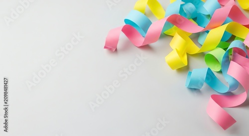Curled pink, yellow, and blue paper streamers on a white surface