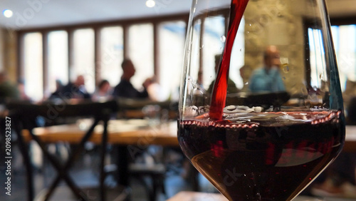 Fotografía Red Wine Pouring into a Glass at a French Bistro in Bordeaux