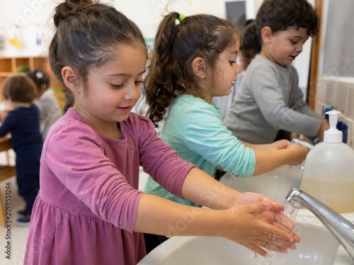 Diverse Group of Young Children Diligently Washing Their Hands in a Bright Preschool Bathroom, Promoting Good Hygiene and Health Habits in an Education