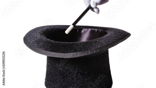 Fotografie White gloved hand holding magic wand over black top hat, isolated on transparent