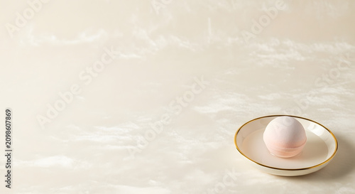 Pink bath bomb in saucer on white fur.