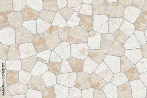 Natural stone wall cladding with irregular shaped rocks in light tan and white colors joined by gray mortar for a rustic exterior facade surface