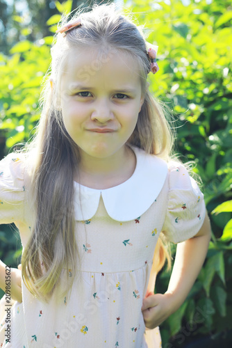 Obraz na plátně Adorable Pouting Girl in Sunny Garden Wearing Floral Dress with Peter Pan Collar