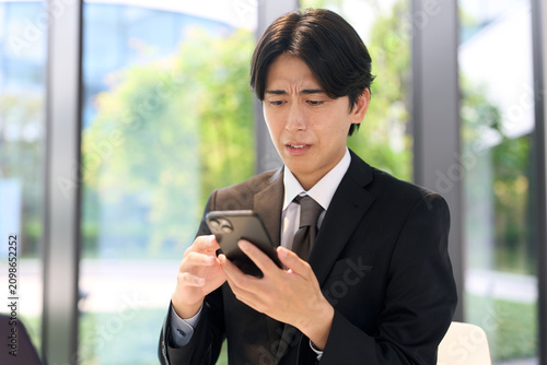 スマホで嫌な通知を見るビジネスマン