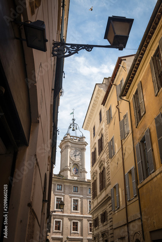 The historic Borromini clock tower framed by narrow city street facades and street lamp in Rome, Italy