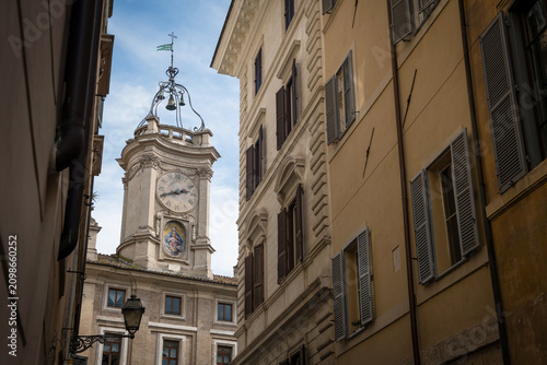 The historic Borromini clock tower framed by traditional Roman facades with wooden window shutters in Rome, Italy